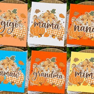 May include: Six square signs featuring pumpkin illustrations with various patterns, including polka dots and checkered designs, accented by bows and acorns. Each sign displays a unique name in cursive script: gigi, mama, nana, mamaw, grandma, and mimi.
