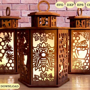 Könnte beinhalten: Drei Holzlaternen mit aufwendigen Ausschnitten, die Bienen, Waben und Blumenmuster zeigen. Jede Laterne hat einen Griff und ein warmes, leuchtendes Inneres. Die Worte "DIGITAL DOWNLOAD" stehen unten.