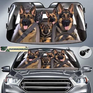Op de afbeelding: Een zonnescherm voor de auto met een groep Duitse herders die veiligheidsgordels dragen en uit de ramen kijken. Het zonnescherm is grijs en heeft een zwarte rand. De honden zijn allemaal bruin en zwart.
