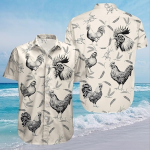 May include: A short-sleeved button-down shirt featuring a repeating pattern of detailed rooster illustrations in black and white on a cream background. The shirt is shown against a beach backdrop with ocean waves and a blue sky.