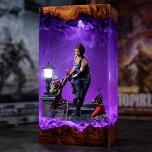 May include: A rectangular wooden lamp featuring a translucent purple resin core with an illuminated scene inside. The diorama depicts a female figure in a blue tank top and dark pants holding a handgun, standing near a zombie and a street lamp.