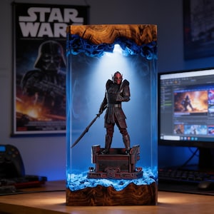 May include: A rectangular lamp featuring a dark wood base and top with a central clear resin section containing a red and black armoured warrior figurine holding a spear. The interior is illuminated with blue light, creating a glowing effect.
