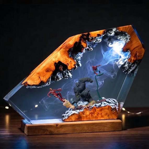 Iron Man and Spider-Man frozen mid-action inside a glowing custom epoxy wood diorama — a superhero collectible that's also functional art lighting.