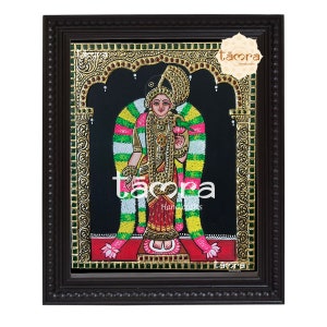 May include: A framed painting of a Hindu goddess with a golden crown and a green and white garland. The painting is on a black background and has gold accents. The frame is brown wood with a beaded border. The painting is signed "taora handicrafts".