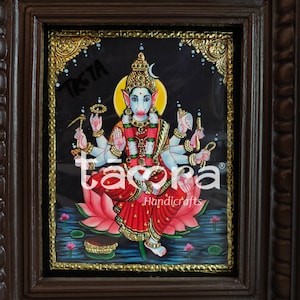 May include: A framed painting of a Hindu deity with multiple arms, sitting on a pink lotus flower. The deity has a blue face and is adorned with gold jewelry. The painting is set against a black background with gold accents.