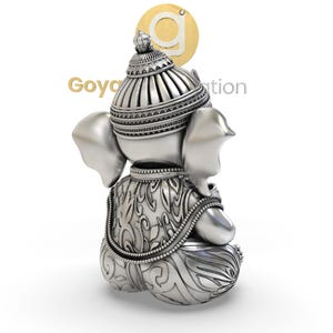May include: A silver-colored statue of Ganesha, the Hindu god of wisdom and prosperity, is depicted from the back. The statue features intricate detailing on the crown, clothing, and base. The logo "Goyal Creation" is visible in the background.
