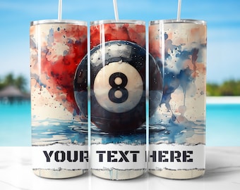 May include: A stainless steel tumbler with a watercolor design of a pool table eight ball. The tumbler has a white background with red, blue, and white watercolor splatters. The text "YOUR TEXT HERE" is printed on the tumbler.