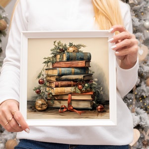 K&ouml;nnte beinhalten: Ein gerahmtes Gem&auml;lde mit einem Stapel antiker B&uuml;cher, die mit Stechpalme und roten Beeren verziert sind. Die B&uuml;cher sind mit einem roten Band zusammengebunden und obenauf befinden sich goldene Ornamente.