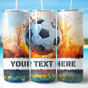Op de afbeelding: Een witte tumbler met een kleurrijk aquarelontwerp van een voetbal met oranje, gele en blauwe accenten. De tekst "YOUR TEXT HERE" is op de tumbler gedrukt.