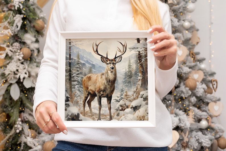 K&ouml;nnte beinhalten: Ein gerahmtes Gem&auml;lde eines braunen Hirsches mit Geweih, der in einem schneebedeckten Wald steht. Der Hirsch blickt direkt auf den Betrachter. Das Gem&auml;lde zeigt einen Hintergrund aus schneebedeckten B&auml;umen und Bergen.