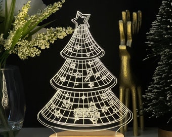 Puede incluir: Lámpara LED con forma de árbol de Navidad iluminado. El árbol es blanco con un diseño de rejilla y decoraciones festivas, incluyendo estrellas y bastones de caramelo. La base es de madera redonda y clara. Las palabras "MERRY CHRISTMAS" son visibles.