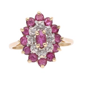 May include: A gold ring featuring a cluster of gemstones. The ring's centerpiece is an oval-shaped ruby, surrounded by smaller rubies and diamonds, creating a floral design. The band is a simple gold band.