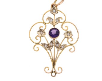 Puede incluir: Colgante dorado con un diseño floral ornamentado. Presenta una piedra preciosa púrpura central, pequeñas perlas y detalles florales. El diseño incluye líneas curvas y un lazo para colgar.