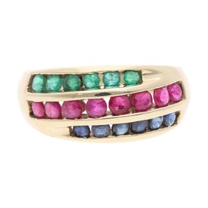 Puede incluir: Un anillo de oro con tres filas de piedras preciosas. La fila superior tiene piedras verdes, la fila central tiene piedras rosas y la fila inferior tiene piedras azules. El anillo tiene un diseño curvo.