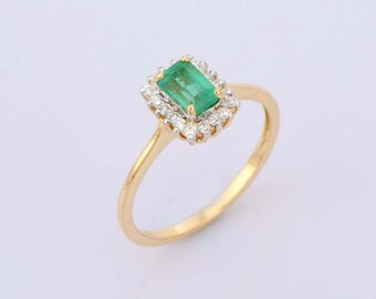 May include: A gold ring with a green emerald gemstone surrounded by a halo of smaller diamonds.