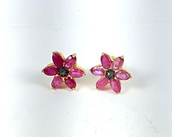 Könnte beinhalten: Ein Paar goldene Ohrringe in Blumenform mit rosa und violetten Edelsteinen und einem kleinen Diamanten in der Mitte jeder Blume.