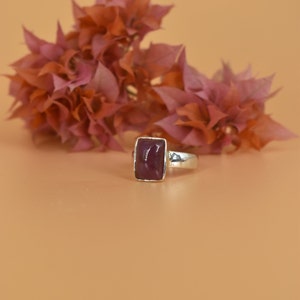 May include: A silver ring with a rectangular, deep purple gemstone.