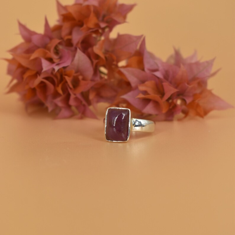 May include: A silver ring with a rectangular, deep purple gemstone.