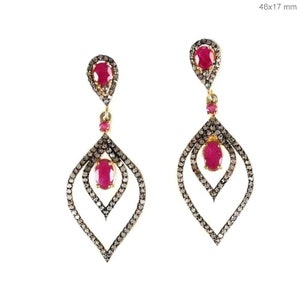 May include: A pair of dangle earrings with a teardrop design. The earrings are made of gold and feature a ruby gemstone and pave diamonds.