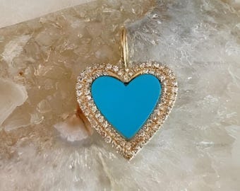 May include: A heart-shaped pendant featuring a bright turquoise center inlay surrounded by a border of small, clear, sparkling stones set in a gold-toned metal frame, complete with a small gold-toned bail at the top for attachment to a chain.