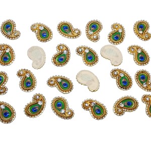 Könnte beinhalten: Eine Sammlung von 20 Pfauenfeder-förmigen Verzierungen mit goldenen Verzierungen und Strasssteinen. Die Verzierungen sind perfekt, um handwerklichen Arbeiten, Schmuck und anderen Projekten einen Hauch von Eleganz zu verleihen.