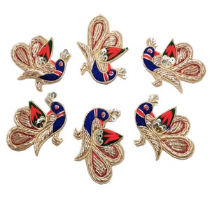 Op de afbeelding: Zes geborduurde pauwenpatches. Elke patch heeft een blauw lichaam, rode en groene accenten en goudkleurige details. De patches zijn versierd met pailletten en hebben een gedetailleerd, gestructureerd uiterlijk.