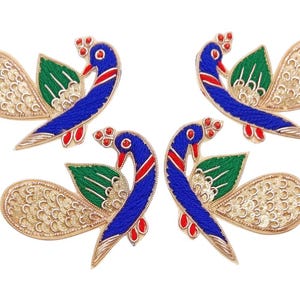 May include: Four embroidered peacock appliques. Each applique features a blue body, red accents, a green leaf, and a gold sequined tail. The peacocks are arranged in a symmetrical pattern against a white background, ideal for embellishing clothing or crafts.