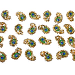 May include: Twenty-five gold-colored paisley-shaped embellishments with a peacock feather design. Each embellishment has a blue and green peacock feather design with white rhinestones around the edges.