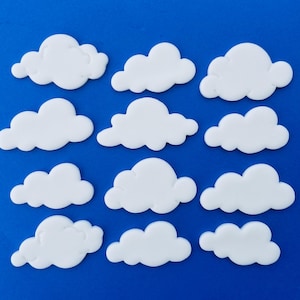 May include: Twelve white cloud-shaped decorations on a blue background. These are perfect for adding a whimsical touch to any craft project.