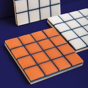 May include: Three square tiles with a grid pattern. The top tile is white with black lines, the middle tile is white with black lines, and the bottom tile is orange with black lines.