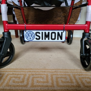 May include: A red walker with black wheels and a white and blue sign that says "SIMON" with a Volkswagen logo.