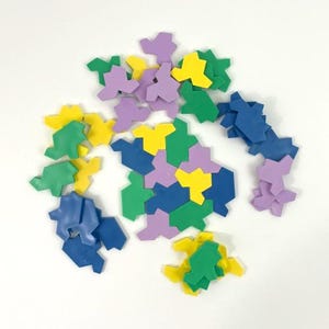 May include: A set of colorful geometric puzzle pieces in shades of green, blue, yellow, and purple. The pieces are made of a soft, flexible material and can be arranged in a variety of patterns.