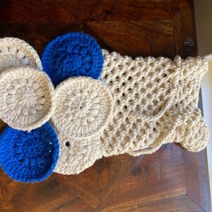 May include: A crocheted bag with a white mesh design and blue and white crocheted circles attached to the front.