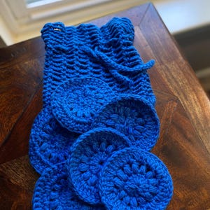 May include: A set of blue crocheted cotton rounds, ideal for removing makeup or cleaning. The rounds are arranged in a pile on a wooden surface.