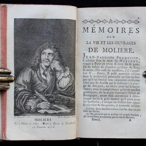K&ouml;nnte beinhalten: Ein aufgeschlagenes antikes Buch mit einer detaillierten Gravur von Moli&egrave;re auf der linken Seite. Die rechte Seite zeigt franz&ouml;sischen Text. Das Buch wird von einem dekorativen, handf&ouml;rmigen Buchhalter aus Metall offen gehalten.