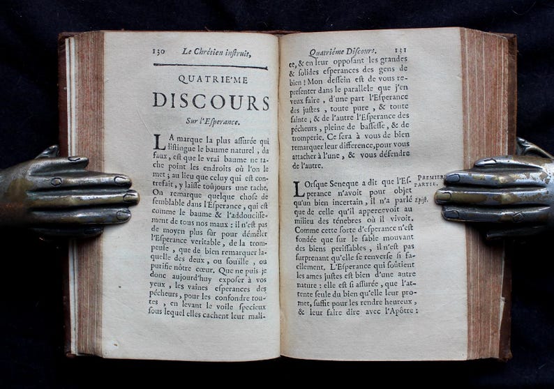 Pode incluir: Um livro antigo aberto com uma capa de couro marrom e p&aacute;ginas amareladas. O livro &eacute; intitulado "Le Chr&eacute;tien Infruit, Quatri&egrave;me Discours Sur l'Esperance". O texto nas p&aacute;ginas est&aacute; em franc&ecirc;s.