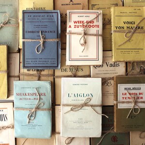Puede incluir: Una colecci&oacute;n de libros antiguos con cubiertas de papel marr&oacute;n y cuerda atada alrededor de ellos. Los libros tienen t&iacute;tulos franceses y est&aacute;n apilados en una pila.