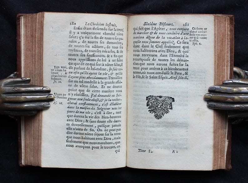 Pode incluir: Um livro aberto com uma ilustra&ccedil;&atilde;o em preto e branco de um p&aacute;ssaro com uma coroa na cabe&ccedil;a. O livro est&aacute; aberto em uma p&aacute;gina com texto em franc&ecirc;s. O texto na p&aacute;gina diz "Sixi&egrave;me Discours".