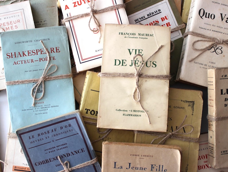 Puede incluir: Una colecci&oacute;n de libros antiguos con cubiertas de papel marr&oacute;n y cuerda atada alrededor de ellos. Los libros tienen t&iacute;tulos franceses, incluyendo "Vie de Jesus" y "La Jeune Fille".