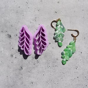 May include: Two pairs of leaf-shaped earrings. One pair is purple and the other is green.