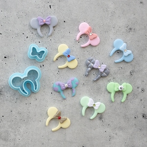 Peut inclure: Assortiment de bandeaux d'oreilles de souris en feutre faits à la main, de couleurs vives et ornés de nœuds. Les bandeaux sont de différentes couleurs, notamment rose, bleu, vert, jaune et gris. Chaque bandeau a un nœud de conception différente.