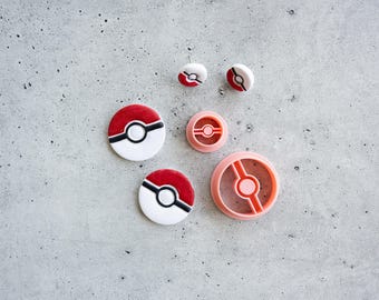 May include: A collection of circular cookie cutters and matching embossed dough cutouts featuring a red, white, and black spherical design. The set includes two small round cutters, two larger round cutters, and two corresponding dough impressions.