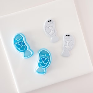 Peut inclure: Quatre emportes-pièces en forme de lamantins. Deux sont blancs et deux sont bleus.