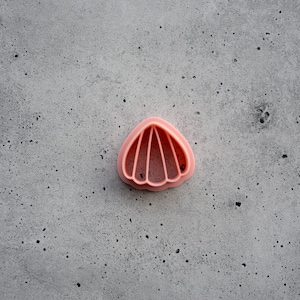 Op de afbeelding: Een roze plastic koekjesvormpje in de vorm van een schelp.