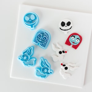 May include: A set of eight blue and white cookie cutters featuring characters from the Nightmare Before Christmas. The cutters include Jack Skellington, Sally, Zero, and a ghost.