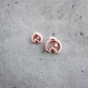 May include: Two pink plastic cookie cutters shaped like Pac-Man, one larger than the other.