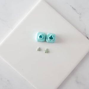 Peut inclure: Deux emporte-pièces en forme de feuille en plastique bleu clair et deux emporte-pièces en forme de feuille en métal argenté sur une surface blanche.