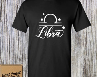 May include: Black t-shirt with a white Libra zodiac symbol and stars. The word "Libra" is written in a cursive font.