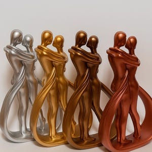 May include: A series of abstract sculptures of embracing figures in silver, gold, bronze, and copper. The figures are intertwined, with flowing lines suggesting movement and connection. The sculptures are displayed against a white backdrop, creating a minimalist aesthetic.