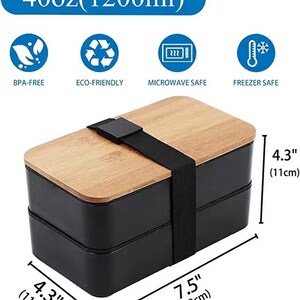 May include: A black and brown two-tiered lunch box with a bamboo lid and a black elastic strap. The lunch box is 7.5 inches wide and 4.3 inches tall. The lunch box is BPA-free, eco-friendly, microwave safe, and freezer safe.